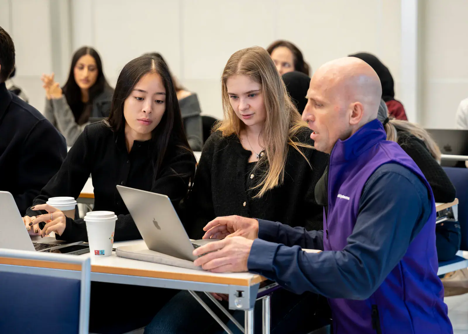 En ansatt fra Anita Systems hjelper to kursdeltakere med Anita Dental på en laptop